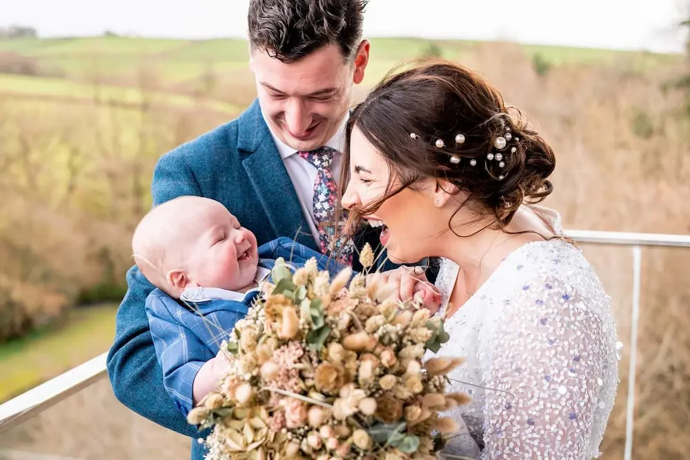 A bride sharing a tender moment with her baby on her wedding day at Tree Top Escape, Devon