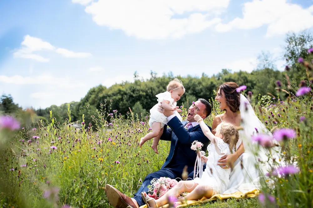 A bride and groom with their children in the meadow at Tree Top Escape, North Devon