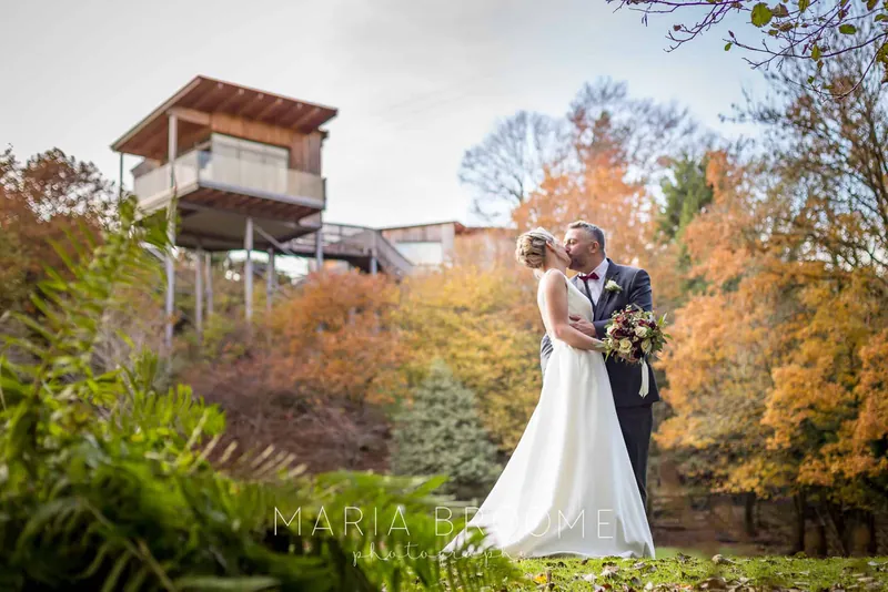Couple kissing among autumn trees with The Nest behind them, Tree Top Escape, Devon