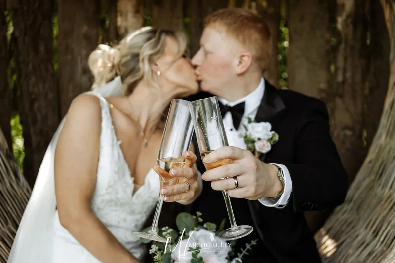 Newlyweds kissing and raising a Prosecco toast after their small wedding at Tree Top Escape